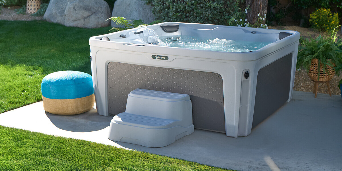Freeflow Monterey spa on a patio beside a lawn, with steps and a side table